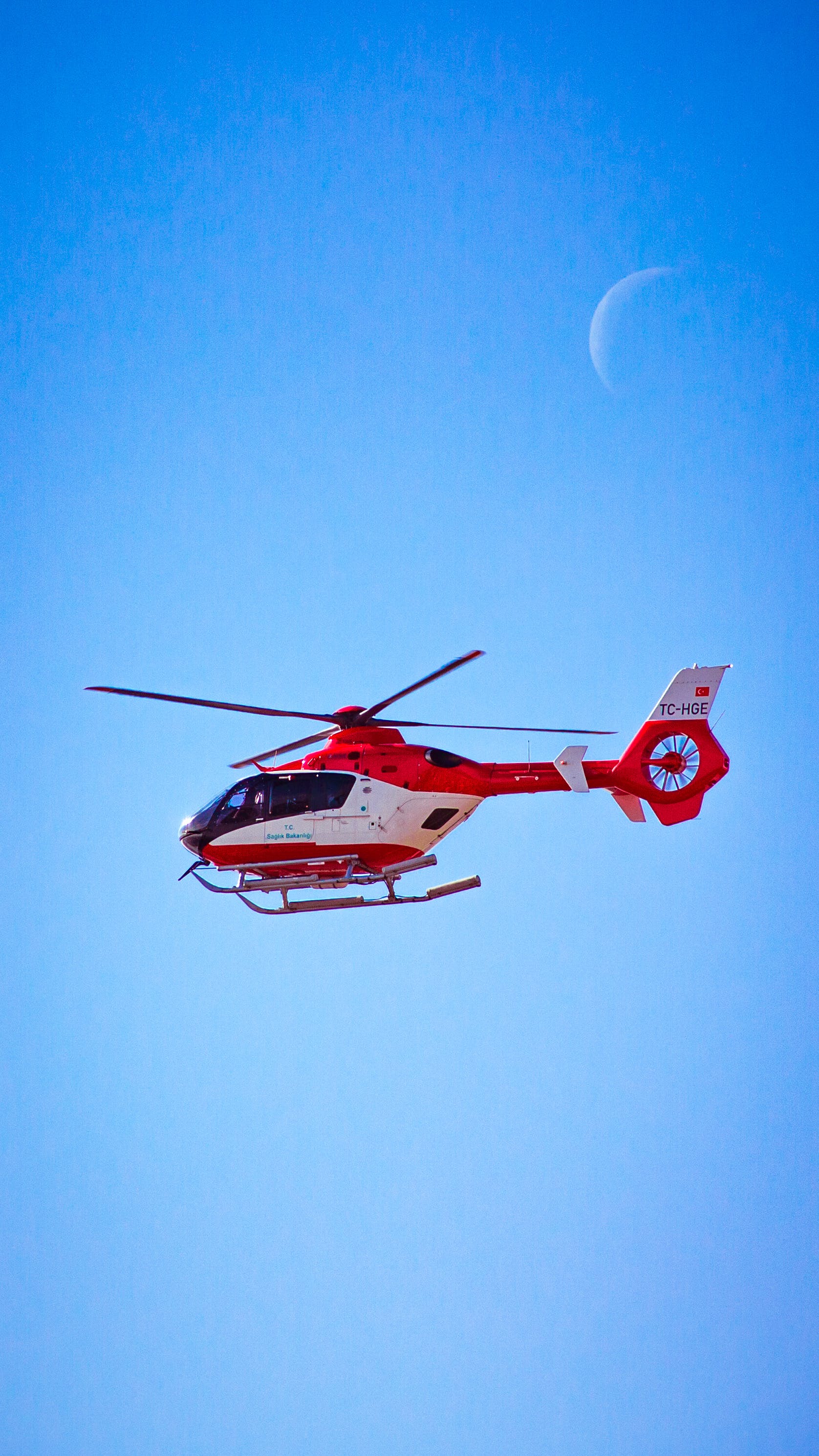 red and white helicopter flying in the sky