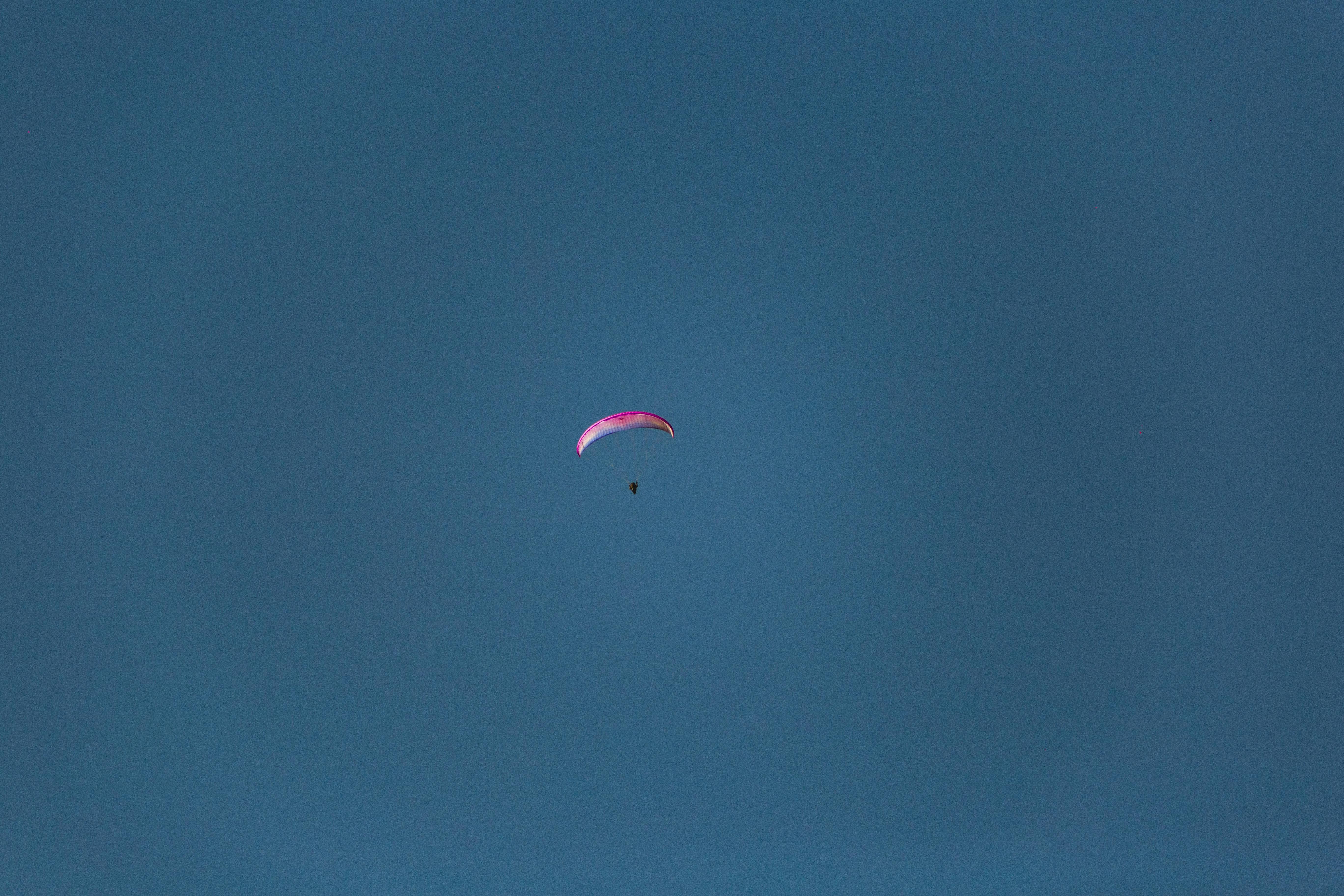 anonymous tourist on parachute flying in sky
