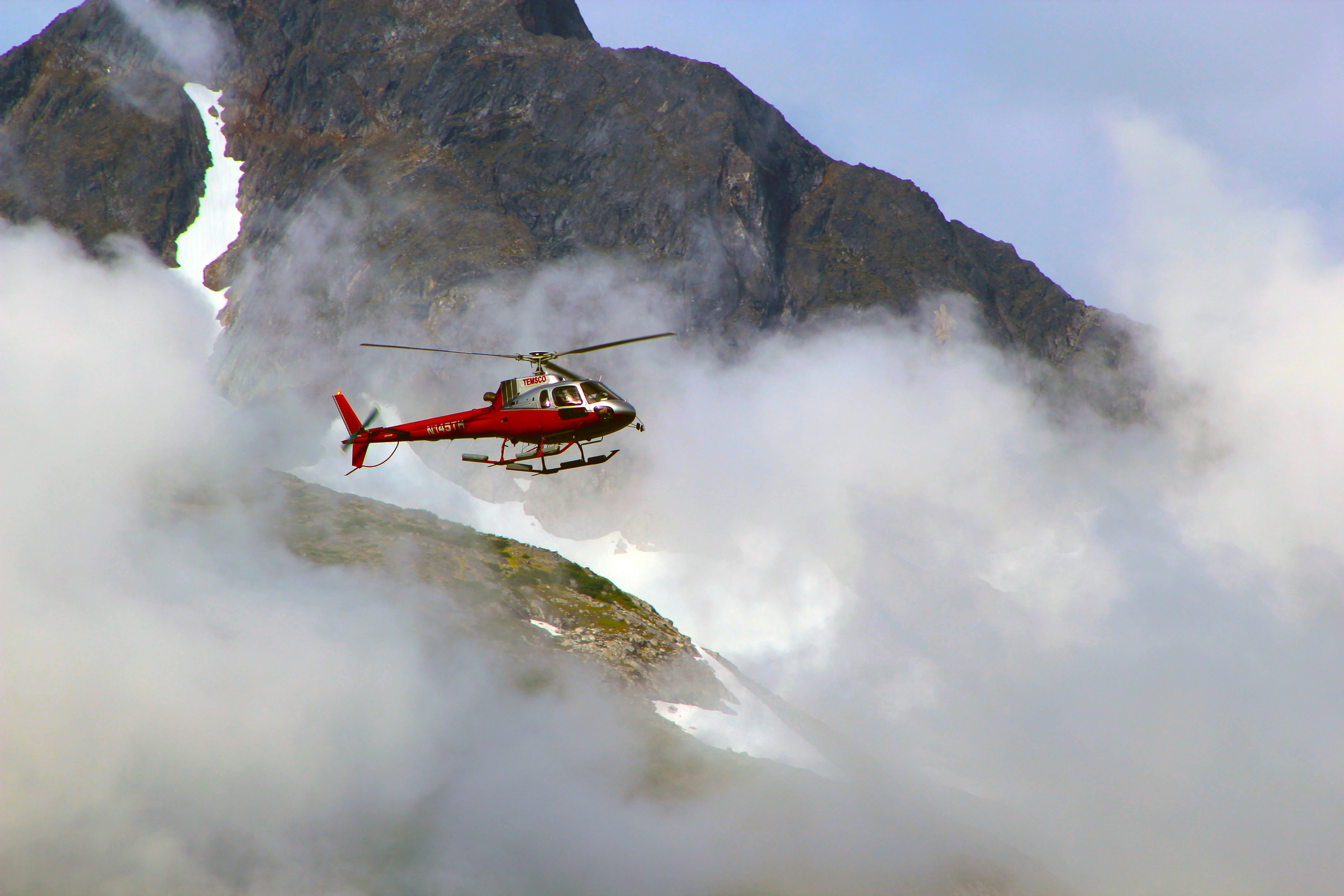 red helicopter on top of foggy mountain